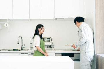 Fototapeta premium キッチンで話す作業着姿の男性と女性（IH・笑顔） 