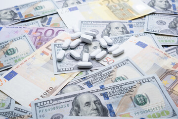 Pills on the background of the dollar and the euro close-up.