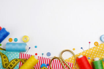 Skeins of sewing thread, multicolored buttons, scissors, needles, thimble, fabric, zipper on a white background.The concept of manual labor,clothing repair,sewing,embroidery,sale of sewing accessories