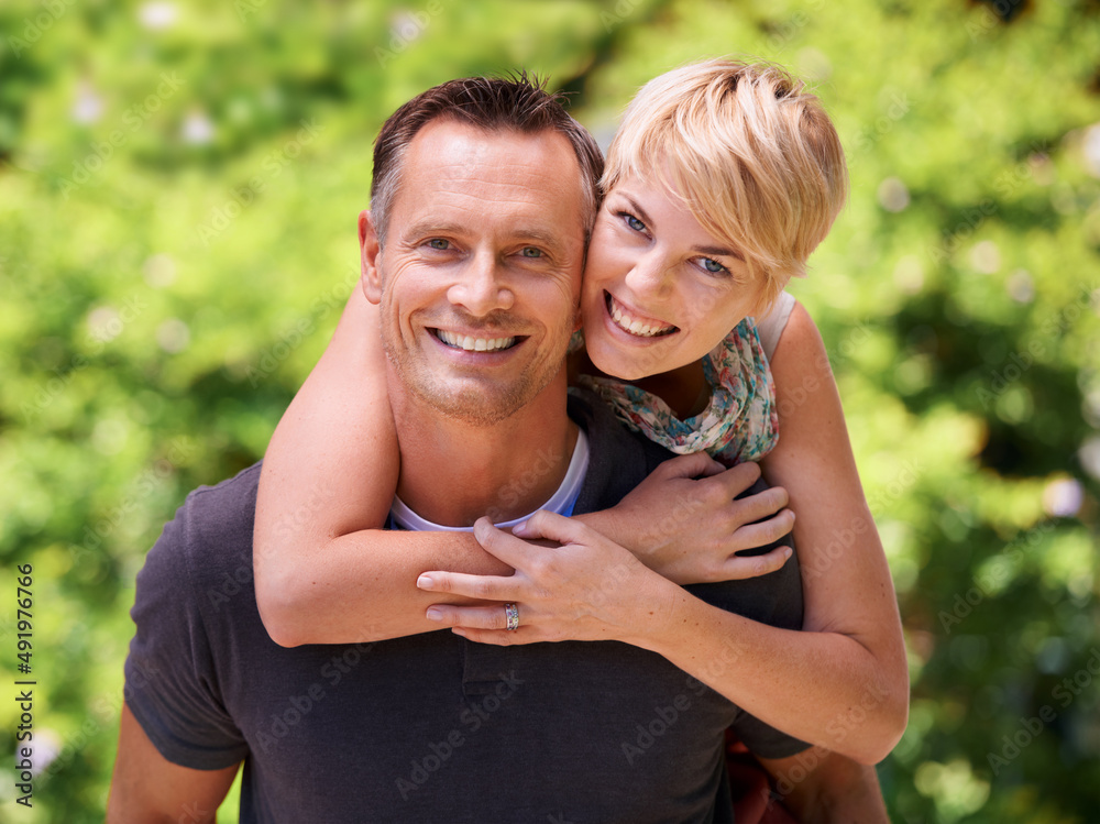 Wall mural Piggyback in the park. Shot of a mature man giving his wife a piggyback ride.