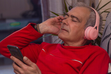 relaxed adult man with headphones and smartphone at home