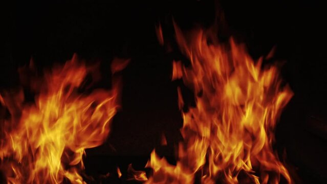 A glow of fire in the dark with copy space. Slow-motion video of fire and flames. A fire pit. Flames and burning sparks close-up, fire pattern.