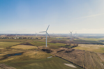 Turbiny wiatrowe, wiatraki produkują energię odnawialną z wiatru na pięknych malowniczych polach oświetlone słońcem - obrazy, fototapety, plakaty