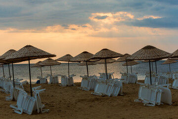 Beach straw umbrella on sunset by the sea, blue hour. amazing waves and clouds. 