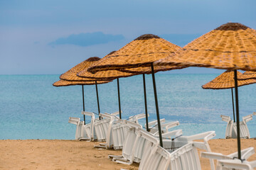 Beach straw umbrella on sunset by the sea, blue hour. amazing waves and clouds. 