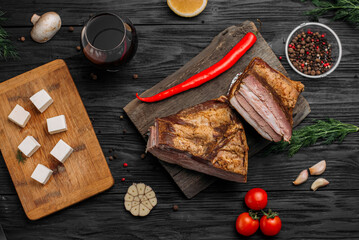 Smoked rib, home-smoked on a wooden background next to vegetables and spices