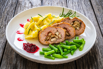 Stuffed pork minced meat with mushrooms, potato puree and green beans on wooden table
