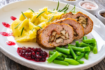Stuffed pork minced meat with mushrooms, potato puree and green beans on wooden table