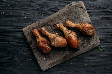 smoked homemade chicken drumstick on a wooden background and an old wooden hot smoked stick