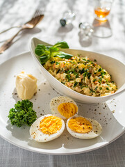 Vegetable mayonnaise salad with hard boiled eggs on white table
