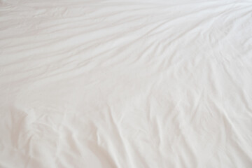 Full frame and top view of wrinkles on a messy white bedsheet in the morning light. placed of hotel, motel, inn room an unmade. abstract surface and texture background.
