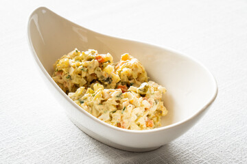 Vegetable mayonnaise salad with hard boiled eggs on white table
