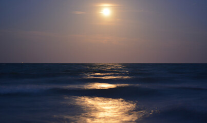 the moon illuminates the waves of the sea