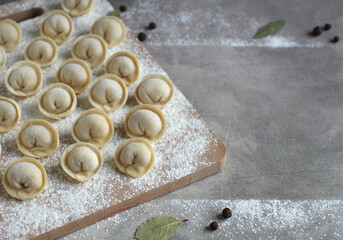 homemade dumplings on a cutting board in rows of flour, pepper and bay leaf