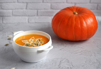 pumpkin soup with pumpkin seeds in a white bowl on a gray background
