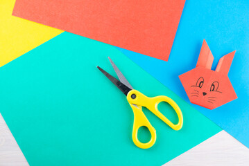 Colored paper with a rabbit and scissors. Horizontal orientation, top view.