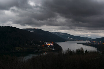 Ciemne chmury nad jeziorem, zapalone latarnie uliczne. Jezioro Żywieckie.