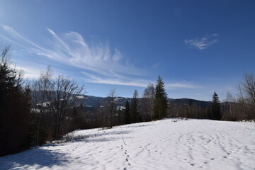 Fototapeta na wymiar Rozwiane chmury nad zimowym górskim szlakiem, Beskid, Polska.