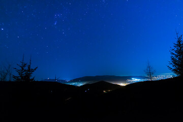 Konstelacje gwiazd na nocnym niebie, w dolinie miasteczko.