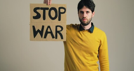 Boy in yellow shirt holds stop war billboard in hand