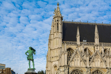 Fototapeta na wymiar Statue of a medieval Tinsmith-Plumber in Place du Petit Sablon with the Église Notre-Dame du Sablon (Church of Our Blessed Lady of the Sablon) in the background, Brussels, Belgium 