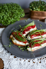 A variety of cheese cream sandwiches assorted with micro greens and grilled peppers on a plate.