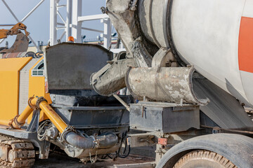 A concrete mixer truck pours mortar into a concrete pump at a construction site. Supply of concrete and mortar for the production of monolithic reinforced concrete works. Close-up.