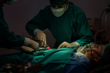 Doctors and nurses work together to perform abdominal surgery to treat patients lying in the...
