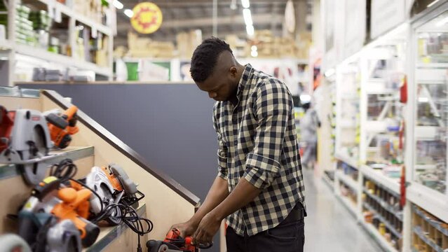 African american buyer selecting tool in building and repair shop indoors