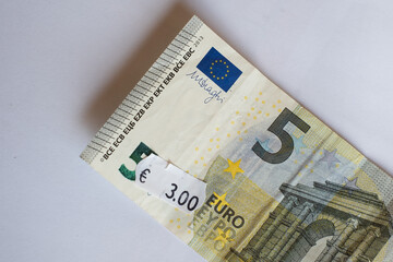 Five euro banknote with three euro price tag. Selective focus on label. Inflation in Europe, hyper inflation, devaluation concept.
