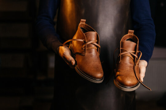 Photo of a pair of quality men's leather shoes in the hands of the master who made them.