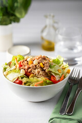 Close up of Tuna salad with lettuce, tomatos, carrot, corn in the white bowl