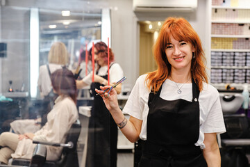 Hairdresser holding a scissor in her hand while standing in the hair beauty salon.