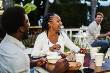 African mother and son eating food truck food outdoor - Focus on senior woman face