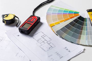Tools for the work of an interior designer on the table. Color palette, laser tape measure and house plan drawings. Close-up. - obrazy, fototapety, plakaty