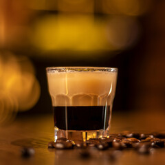 shot with coffee in the glass and coffee beans on wooden table in bar square