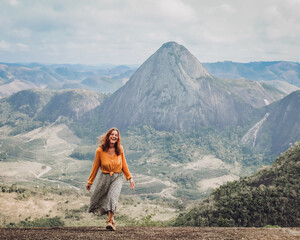 Naklejka na ściany i meble mulher com blusa amarela caminhando com montanhas ao fundo em Pancas, Espírito Santo