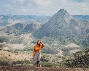 mulher com blusa amarela caminhando com montanhas ao fundo em Pancas, Espírito Santo