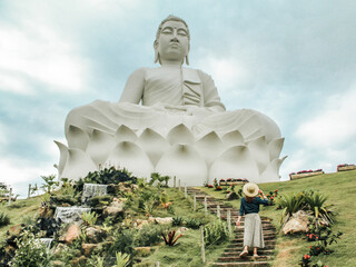 Fototapeta premium mulher não identificada de chapéu e saia em frente à maior estátua de Buda do Brasil, em Ibiraçu, Minas Gerais