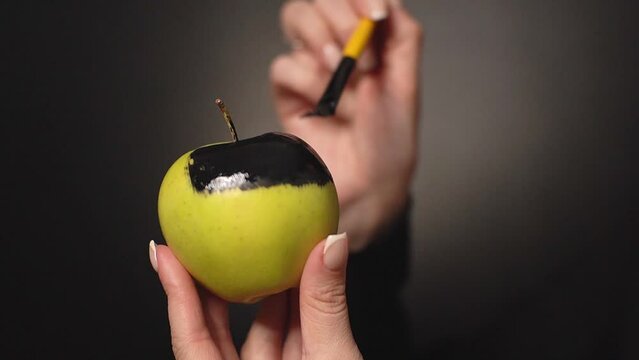 girl paints an apple black