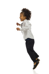 Black little boy in elegant clothesis jumping and laughing. Side view, full length, isolated.