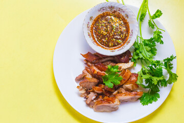 Grilled pork mask was marinated with minced coriander root, black pepper and garlic and served with Thai spicy sauce (Jaew sauce).