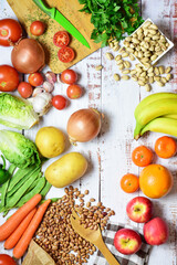 Vertical shot. Assortment of healthy foods, vegetables, fruit, legumes, on rustic white wooden boards. Zenith view and copy space.