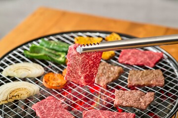 焼肉をトングで持つ