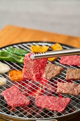 焼肉をトングで持つ