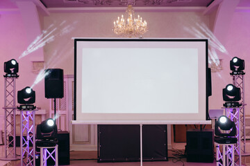 Party setting. A view to the projection screen equipment at the decorated background of a banquet...