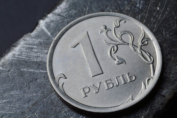 Russian coin denominated 1 ruble. shines on a scratched metal surface. close-up. translation of the text on the coin 