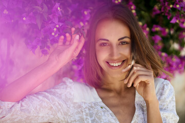 Close up beauty portrait woman with charming smile and smooth skin in spring garden with pink flowers