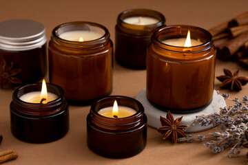 A set of different aroma candles in brown glass jars. Scented handmade candle. Soy candles are burning in a jar. Aromatherapy and relax in spa and home.