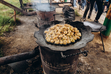 Potatoes in a disc on fire roast in the mountains of Ukraine for the festival of tourists. Delicious potatoes in uniforms.